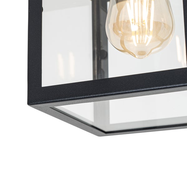 Detailansicht einer modernen Leuchte in Laternenform mit Metallrahmen, Glaseinsaetzen und sichtbarem LED-Filament-Leuchtmittel.