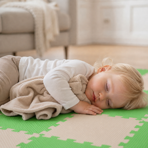 Kleinkind schläft auf einer Puzzlematte aus Schaumstoff im Wohnzimmer, der Boden ist mit ineinandergreifenden Bodenfliesen für Kinder ausgelegt.