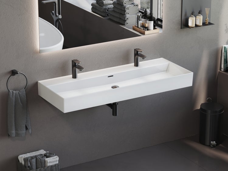 Modernes Badezimmer mit weißem Doppelwaschbecken aus Keramik, zwei schwarzen Armaturen und einem beleuchteten Spiegel an einer grauen Wand.