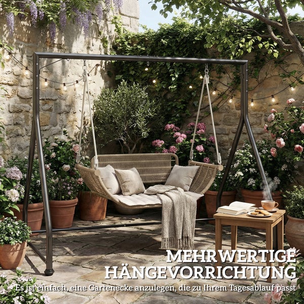 Moderne Garten-Hängeschaukel aus Geflecht mit Kissen an einem Metallgestell in einem bepflanzten Patio mit Steinmauer.