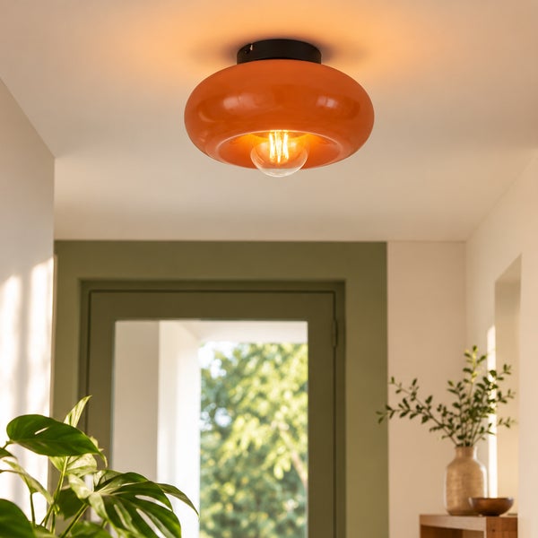 Moderne Deckenleuchte mit orangefarbenem Glasschirm und sichtbarem Leuchtmittel in einem Wohnraum