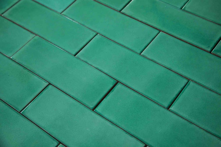Glänzende grüne rechteckige Wandfliesen im Mauerverband.