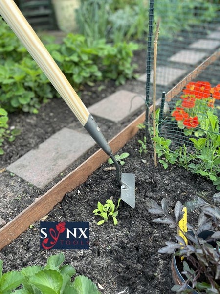 Gartenhacke mit Holzstiel im Einsatz in einem Gartenbeet.