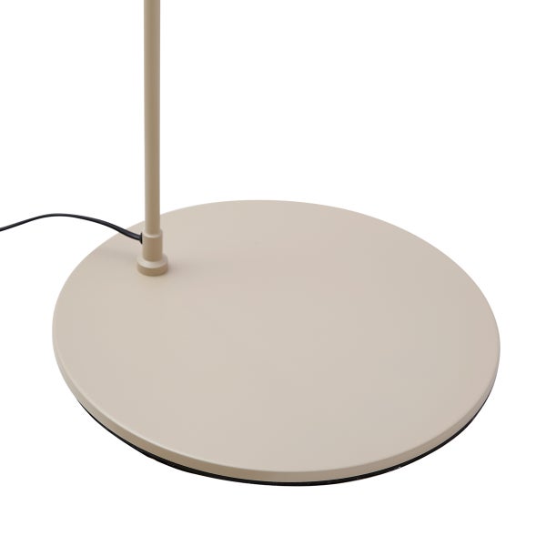 Runder beiger Fuß einer Stehleuchte mit einer dünnen Stange und einem schwarzen Stromkabel.