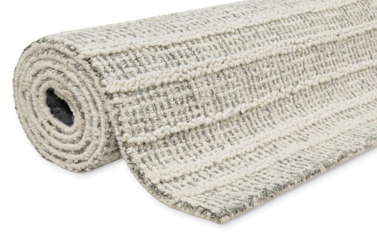 Gerollter Teppich mit strukturierter, gestreifter Oberfläche in Grau und Weiß.