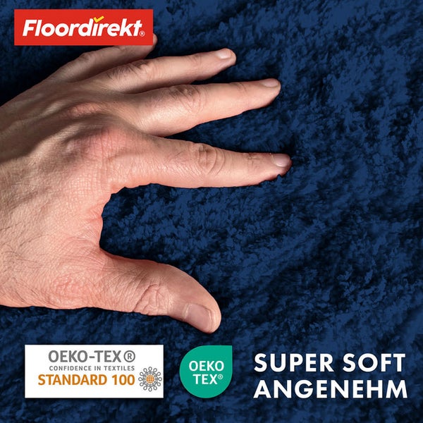 Detailansicht eines blauen Teppichs mit einer Hand darauf, daneben die Logos von Floor direkt und Oeko-Tex sowie der Schriftzug Super Soft Angenehm