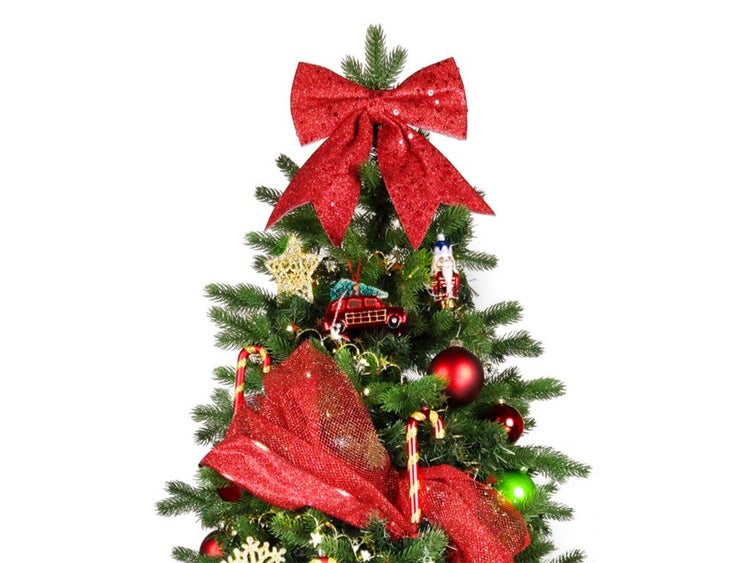 Weihnachtsbaumspitze mit großer Schleife und festlicher Dekoration wie Sterne, Zuckerstangen und Kugeln an einem künstlichen Weihnachtsbaum