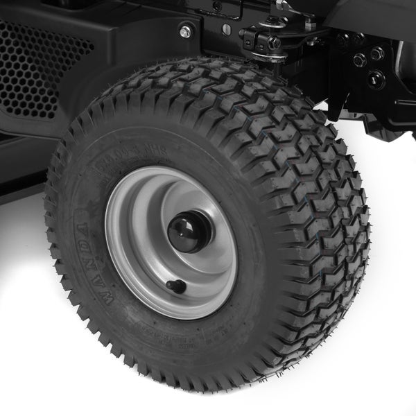 Nahaufnahme eines schwarzen Reifens mit Blockprofil auf einer silbernen Metallfelge, montiert an einem Rasentraktor.