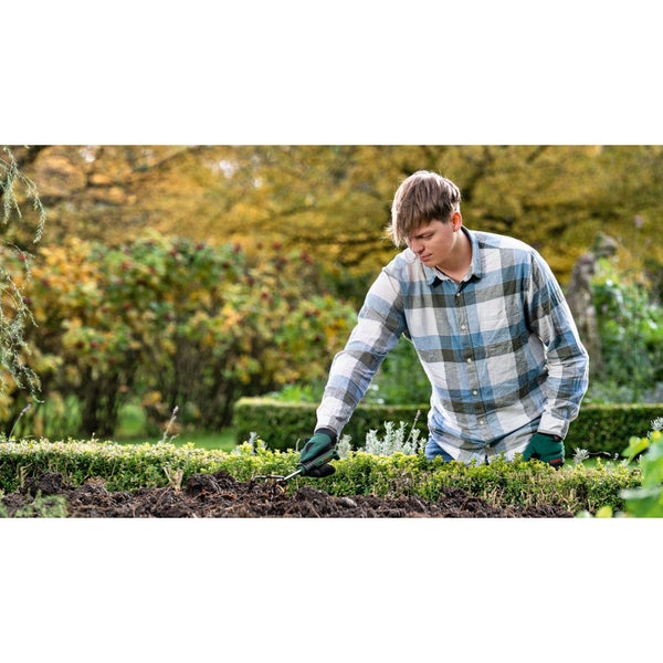 Ein Mann arbeitet mit einer Gartenhacke im Gartenbeet.