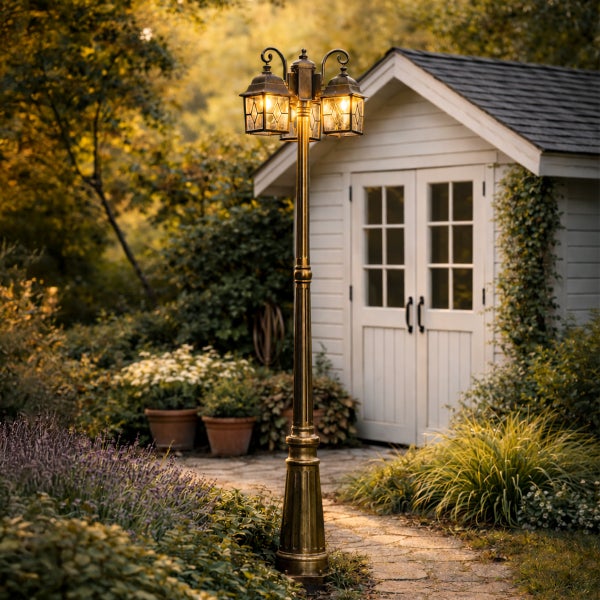 Dreiflammiger Kandelaber aus Bronze im Garten vor einem weißen Gartenhaus und Steinweg.
