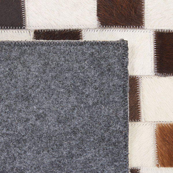 Nahaufnahme eines Patchwork-Teppichs aus Kuhfellquadraten mit Filzrückseite und Zickzack-Stichen.
