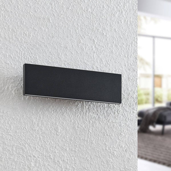 Rechteckige Wandleuchte in Schwarz mit matter Oberfläche an einer strukturierten Wand montiert.