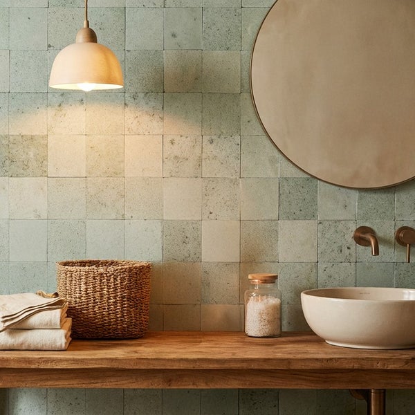Modernes Badezimmer mit quadratischen Fliesen an der Wand, Holzwaschtisch, Aufsatzwaschbecken, runder Spiegel und eine hängende Leuchte.