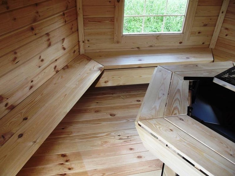 Innenansicht eines Gartenhauses mit Holzboden, Holzwänden, Holzbänken und Fenster