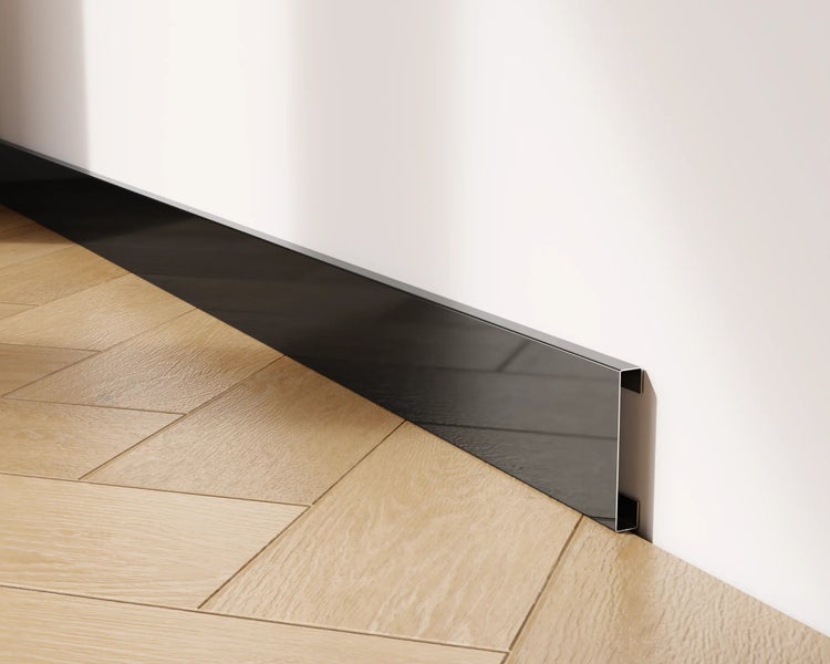 Sockelleiste aus Metall an einer weißen Wand und einem Parkettboden
