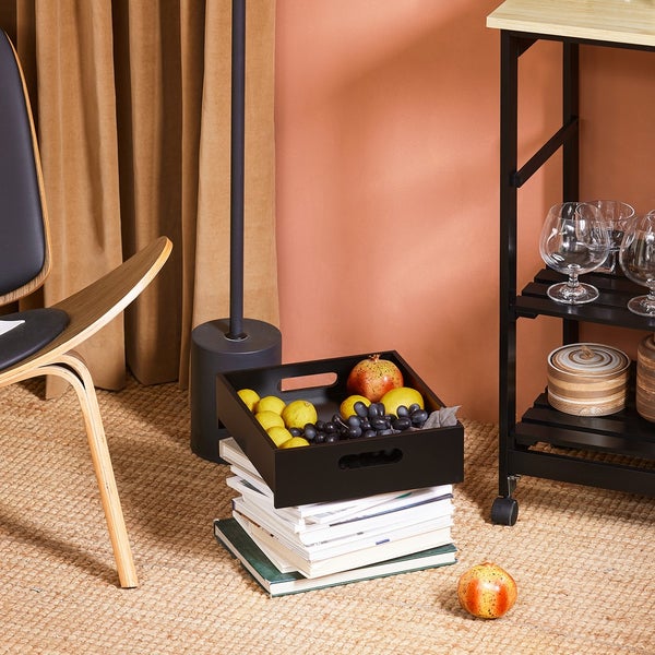 Dekorative Szene mit Tablett auf Bücherstapel neben Stuhl und Barwagen