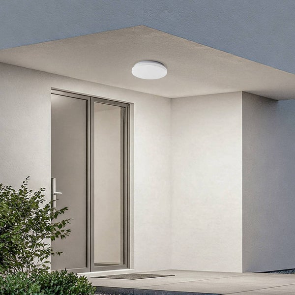 Runde weiße Außen-Deckenleuchte montiert in einem modernen Eingangsbereich mit Glastür und hellen Wänden.