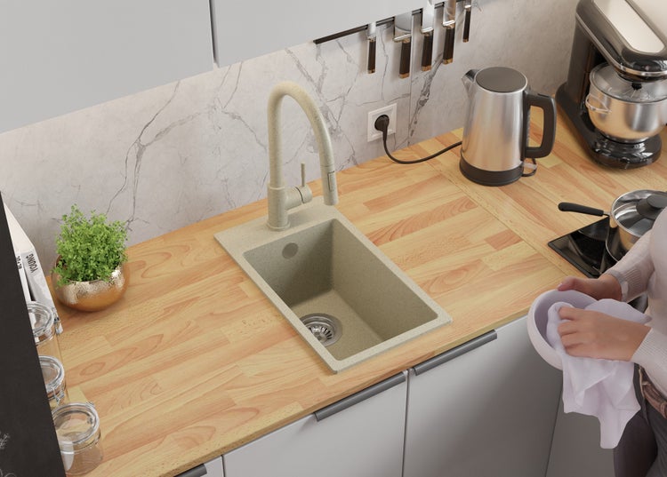 Küchenszene mit Spüle, Armatur, Arbeitsplatte aus Holz, Elektrogeräten und Person