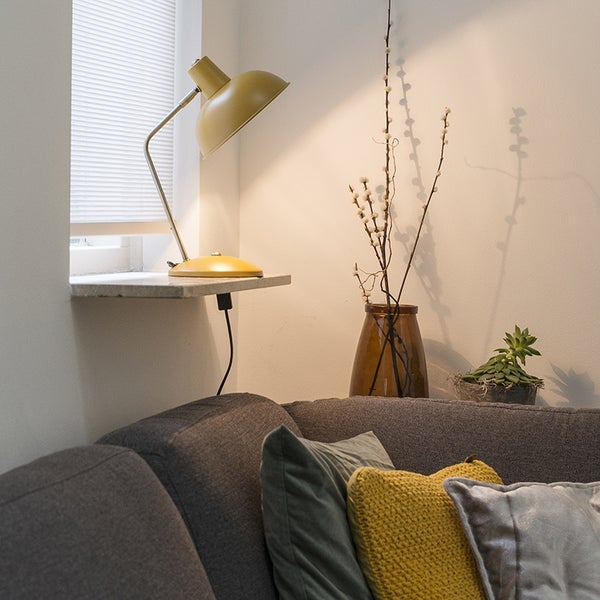 Wohnzimmerszene mit grauer Couch, Kissen, Tischlampe und Dekoration