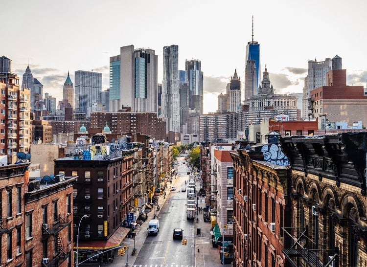 Fototapete mit Stadtansicht von New York City. Blick durch eine Straßenschlucht mit Backsteinhäusern auf das One World Trade Center und Wolkenkratzer.