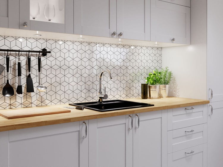 Helle Küche mit Holzarbeitsplatte, schwarzer Einbauspüle, Chromarmatur und Fliesenspiegel mit geometrischem Muster.