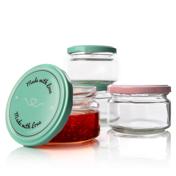 Mehrere Einmachgläser mit verschiedenen Deckelfarben, eines davon mit Marmelade gefüllt