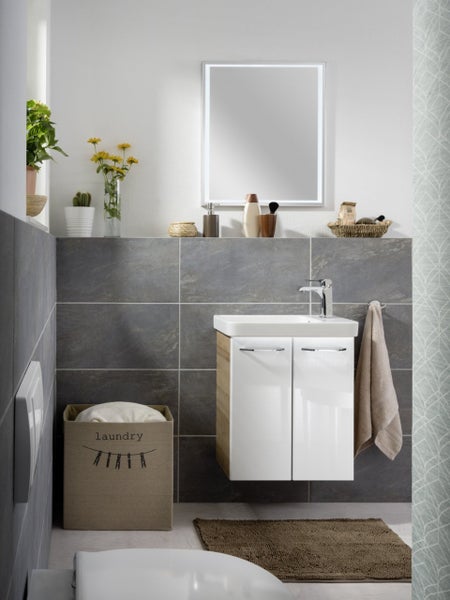 Helles Badezimmer mit Waschtisch, Spiegel, Wäschekorb und Accessoires