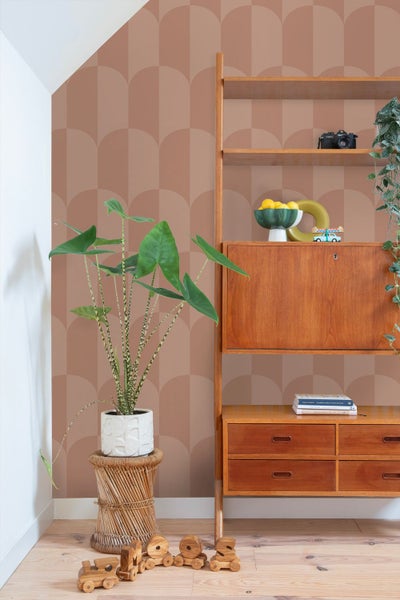 Wohnraum mit Vliestapete mit geometrischem Bogenmuster in einem modernen Raum mit einem Holzregal und einer Zimmerpflanze auf einem Rattan Hocker