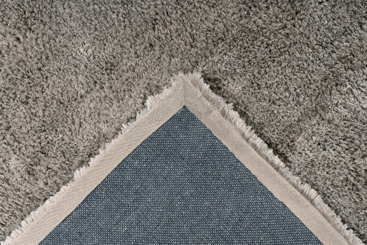 Hochflor-Teppich Shaggy mit Detailansicht der gewebten Rückseite und Kante.