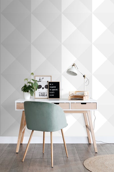 Schreibtisch mit Stuhl, Lampe und Dekoration vor einer geometrischen Tapete