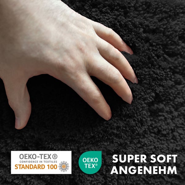 Detailaufnahme eines schwarzen Teppichs mit weicher Textur, auf dem eine Hand liegt; Öko-Tex Standard 100 Siegel