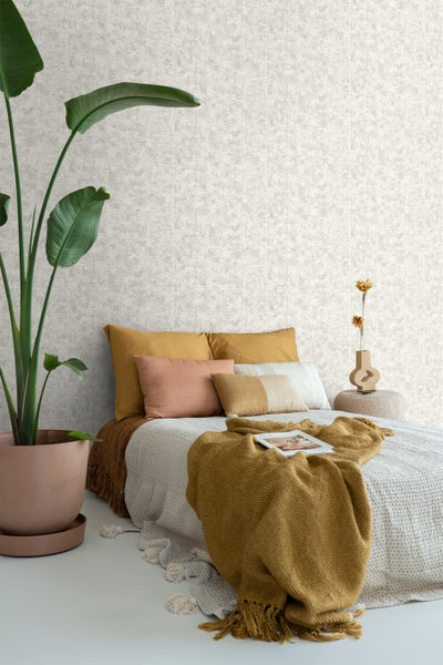 Schlafzimmer mit gemusterter Tapete, Bett, Kissen und Zimmerpflanze