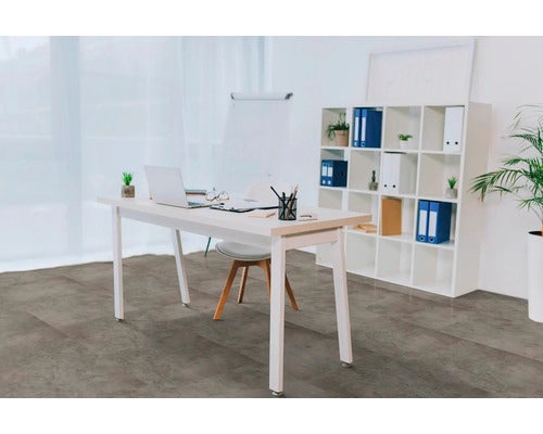 Heller, moderner Büroraum mit großformatigem Bodenbelag in dunkelgrauer Betonoptik, weißem Schreibtisch und Regal.