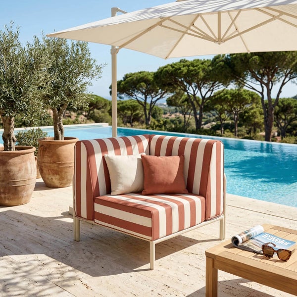Moderner gestreifter Lounge-Sessel mit Metallgestell auf einer Steinterrasse am Pool unter einem Sonnenschirm.