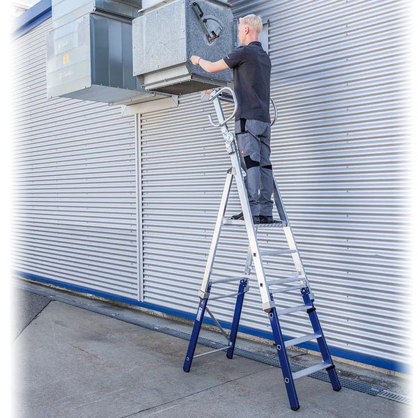 Eine Person steht auf einer Podestleiter und arbeitet an einer Lüftungsanlage.