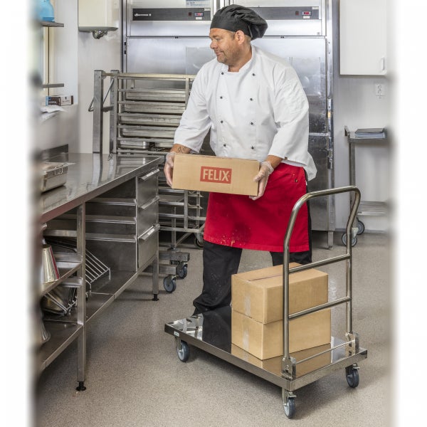 Koch mit Kisten auf einem Edelstahlwagen in einer Restaurantküche