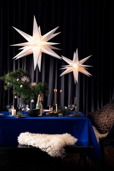 Festlich gedeckter Tisch mit Sternleuchten, Kerzen und Tannenzweigen für eine weihnachtliche Atmosphäre.