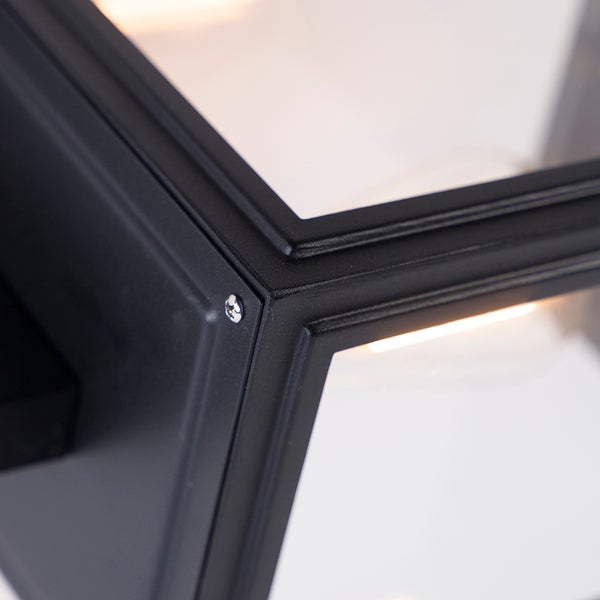 Nahaufnahme einer modernen Außenwandleuchte mit schwarzem Metallrahmen, Glaseinsätzen und sichtbarer Schraube.