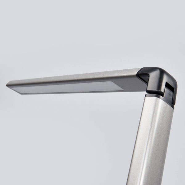 Schwenkbarer Kopf einer modernen LED-Schreibtischleuchte aus silberfarbenem Metall und schwarzem Kunststoff.