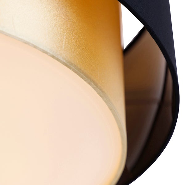 Nahaufnahme eines Lampenschirms mit goldener Innenseite und schwarzem Außenelement aus Stoff.