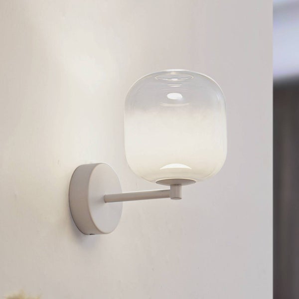 Moderne Wandleuchte mit rundem Glasschirm und weißer Halterung, eingeschaltet an einer Wand montiert.