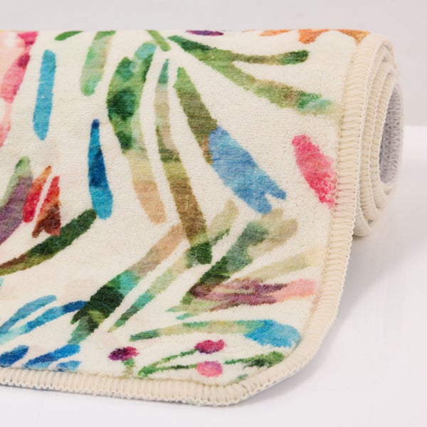 Gerollter Teppich mit buntem Blattmuster und Blumenmotiven, weiche Oberfläche, gekettelte Kante.