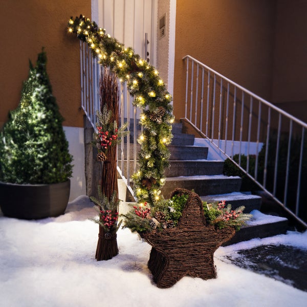 Dekorierte Außentreppe mit Lichterkette, Strauch und Sternkorb für eine weihnachtliche Atmosphäre