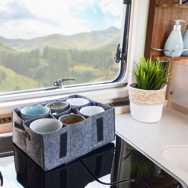 Filztasche als Tassenhalter für Wohnmobil oder Küche mit sechs Fächern auf einem Herd vor einem Fenster mit Bergpanorama
