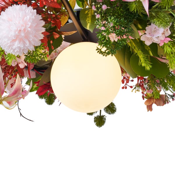 Detailansicht einer runden Leuchte mit Dekoration aus künstlichen Blumen und Blättern.