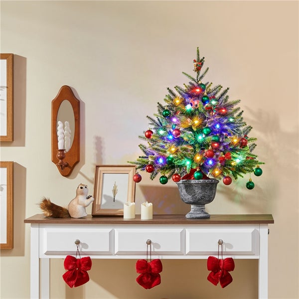 Dekorativer Weihnachtstisch mit geschmücktem Baum, Beleuchtung und Ornamenten