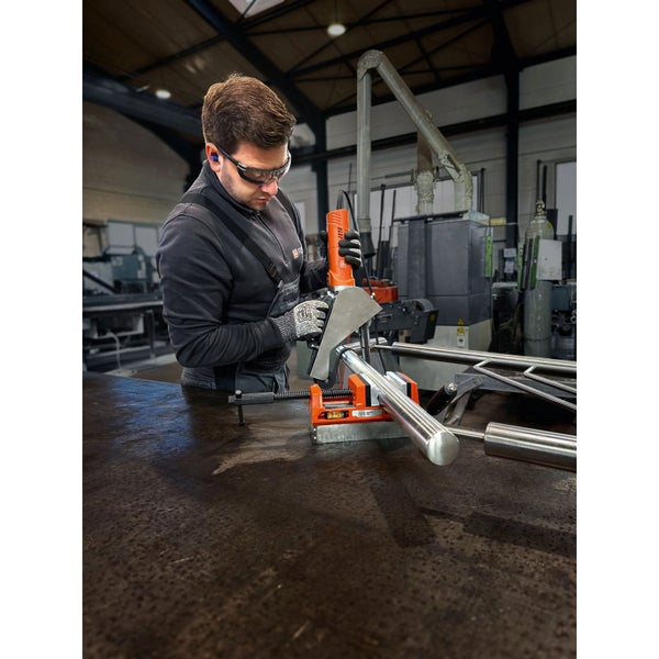 Mann mit Schutzbrille und Gehörschutz, der mit einer Rohrsäge ein Metallrohr bearbeitet