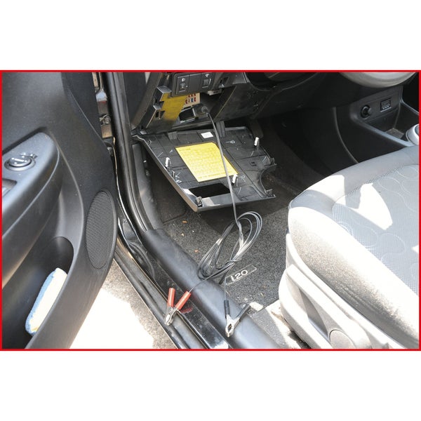 Innenraum eines Autos mit offenem Sicherungskasten und angeschlossenem Diagnosekabel