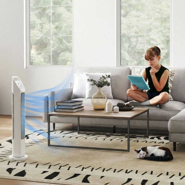 Weißer Turmventilator in einem hellen Wohnzimmer mit Sofa, Couchtisch und Teppich. Eine Person sitzt auf der Couch und liest ein Buch.