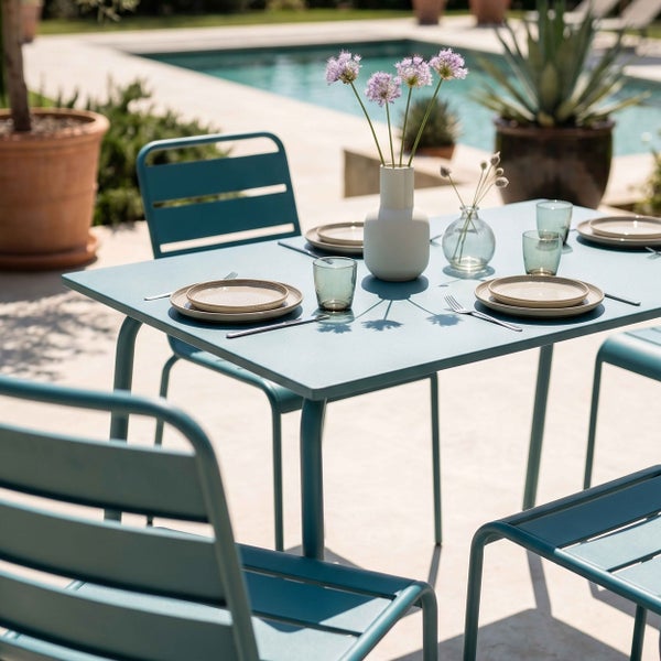 Moderne Garten-Essgruppe aus Metall mit rechteckigem Tisch und Stühlen auf einer hellen Terrasse neben einem Pool.